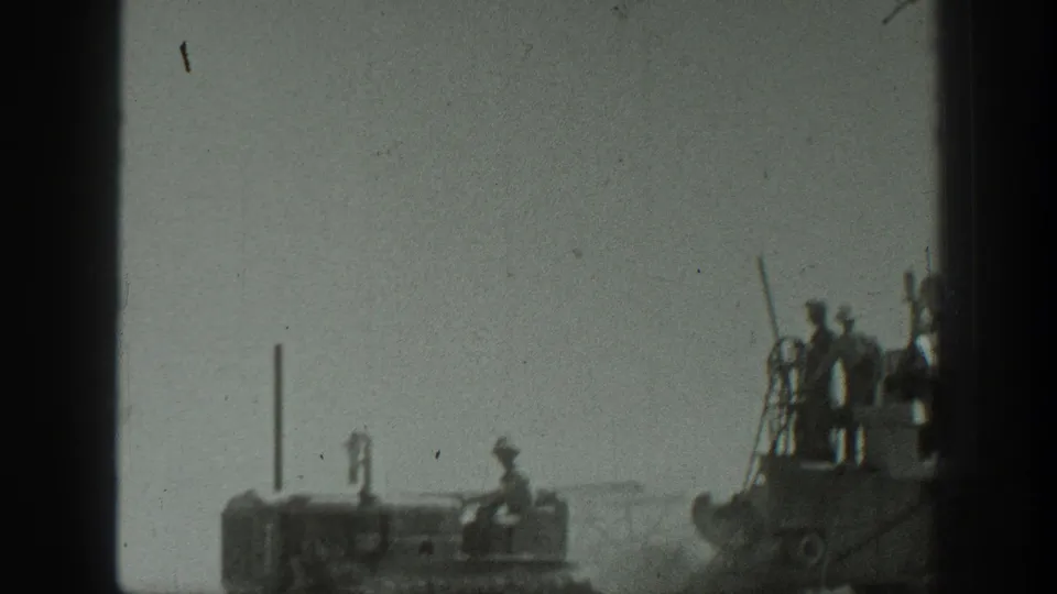 Uniformed personnel stand on a large armored vehicle in a dusty California field, with another vehicle visible nearby.