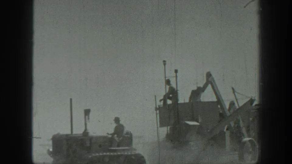 California 1939 frame with a tractor and a large grader-like machine, both carrying or attended by workers.