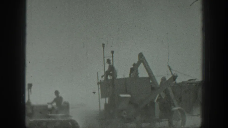 California 1939 home-movie view of a tractor beside heavy construction equipment with workers positioned on both machines.
