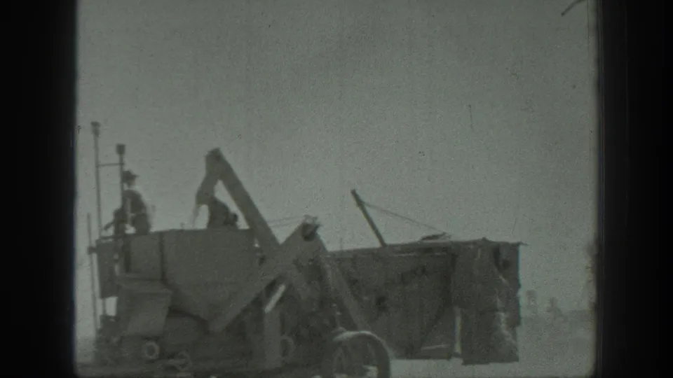 1939 California 8mm frame showing workers on a large industrial hopper or machine in a dusty outdoor worksite.