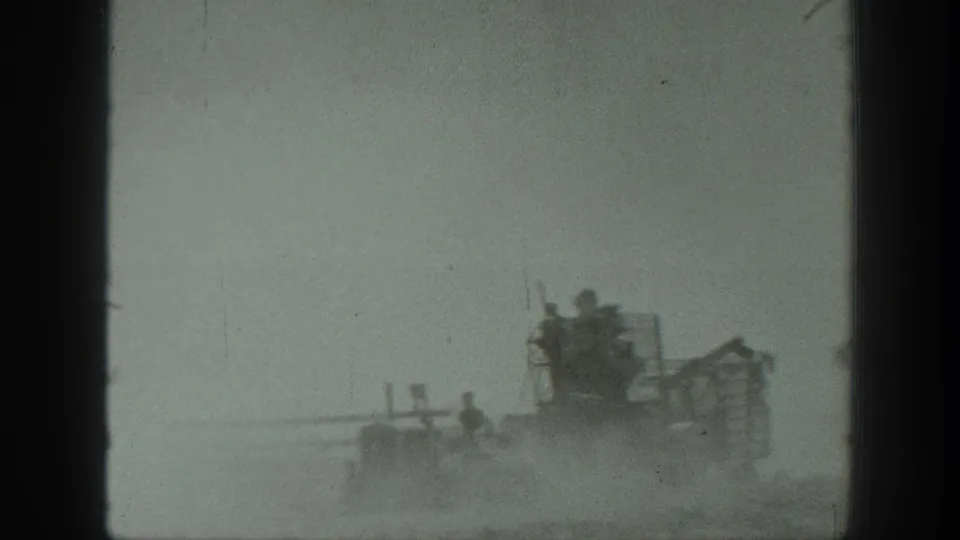 1939 California frame with workers and a work vehicle seen through dust, framed by visible 8mm gate edges.