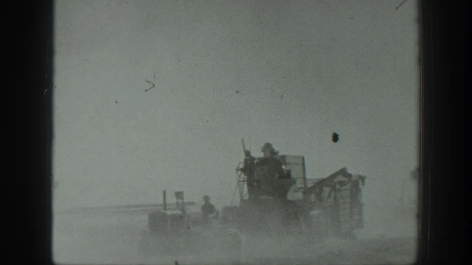 1939 California field machinery appears in a dusty open landscape, with several workers visible on or near the equipment.