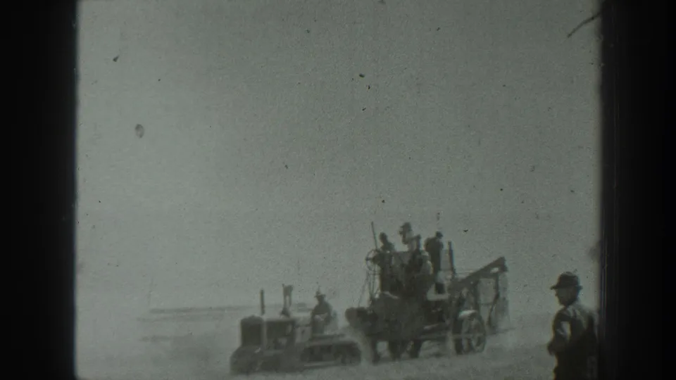 1939 California 8mm frame showing uniformed personnel gathered near a tractor-like vehicle and artillery equipment on dusty open ground.