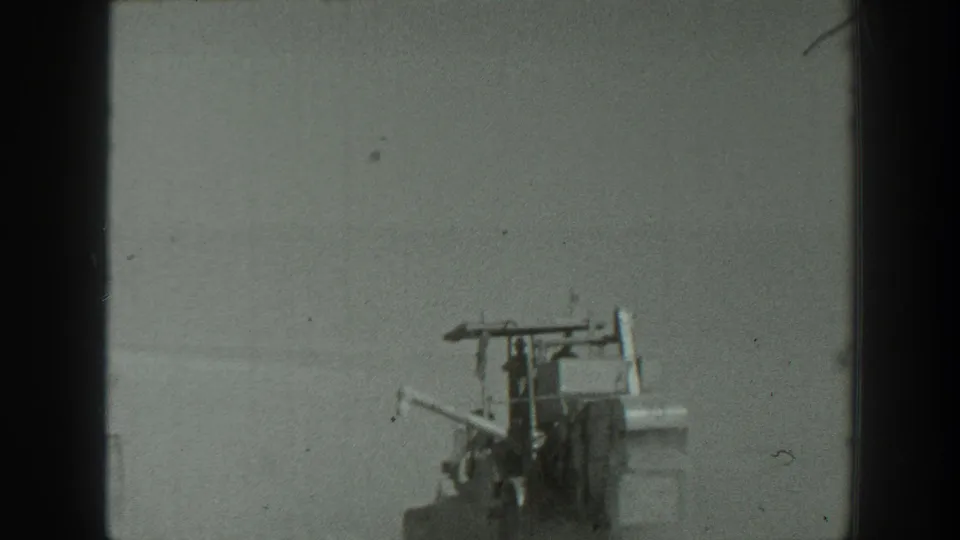 1939 California 8mm frame with an artillery piece or field apparatus and nearby personnel on a sparse open training ground.