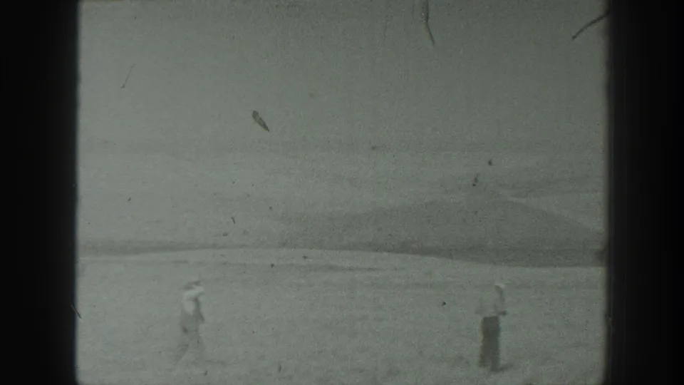 1939 California 8mm frame with two distant figures crossing or standing on open ground near low hills after the military equipment shot.
