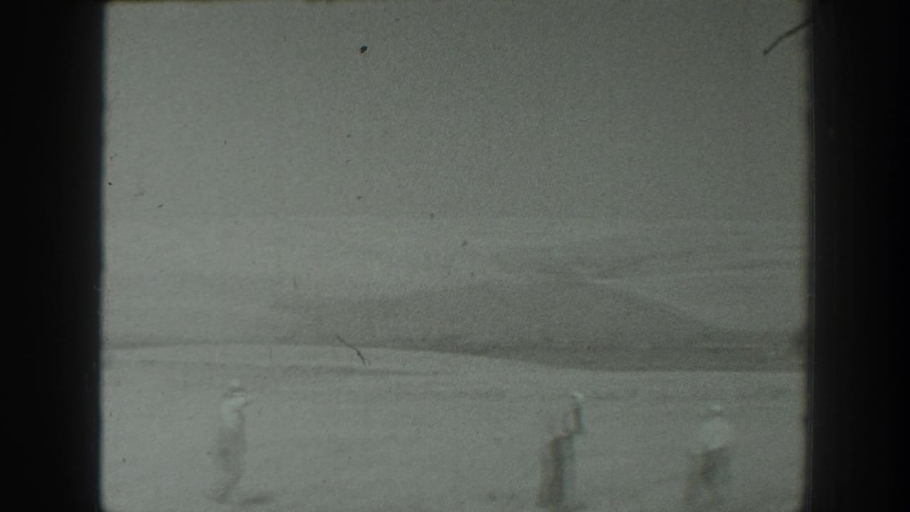 1939 California home-movie frame showing distant people moving across a wide, flat natural landscape.