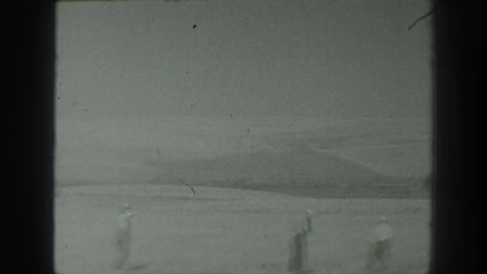 1939 California home-movie frame showing distant people moving across a wide, flat natural landscape.