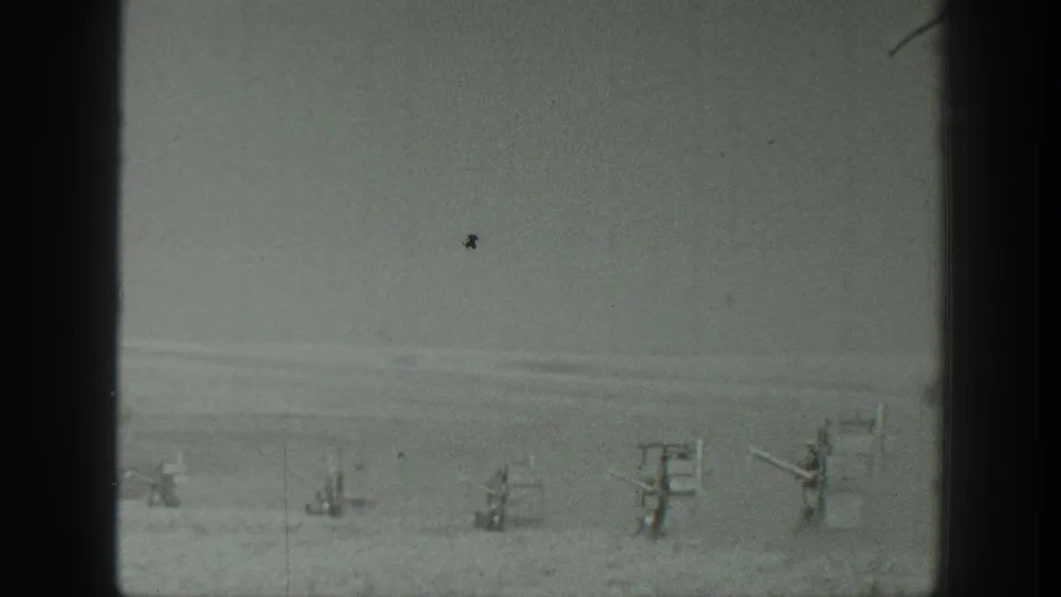 1939 California 8mm frame showing distant military-style gun emplacements on a flat desert landscape with no visible people.