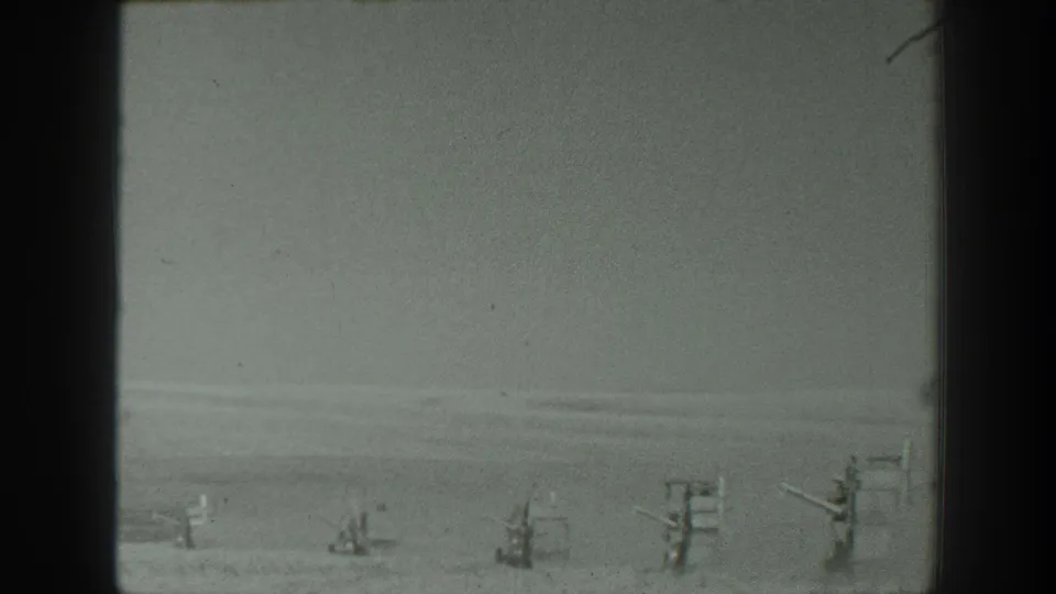 1939 California home-movie frame with a row of military-style installations visible across a pale desert horizon.