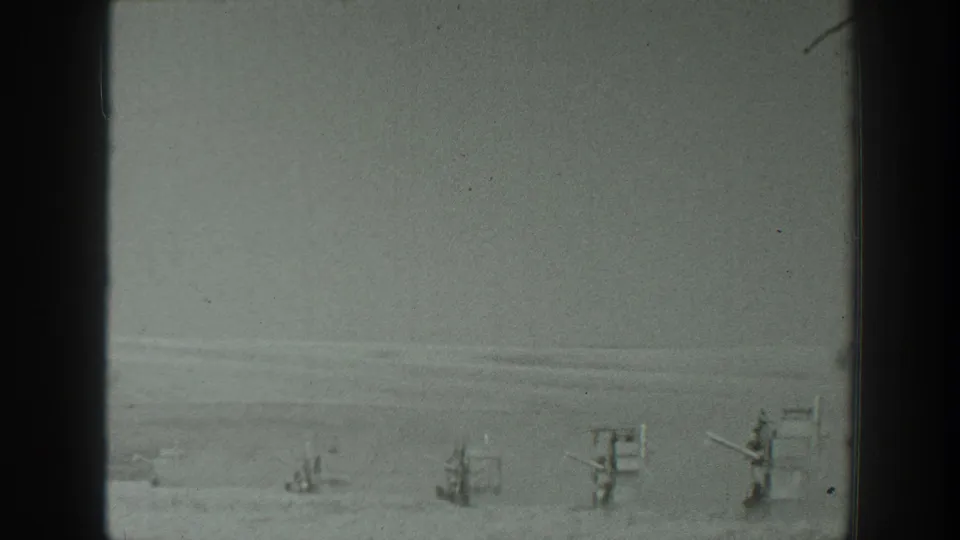 Grainy 1939 California desert frame showing distant military-style emplacements in a static home-movie view.
