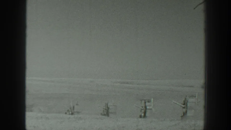 Archival 8mm frame from California, 1939, with blurred upright figures or structures set far across a snowy open area.