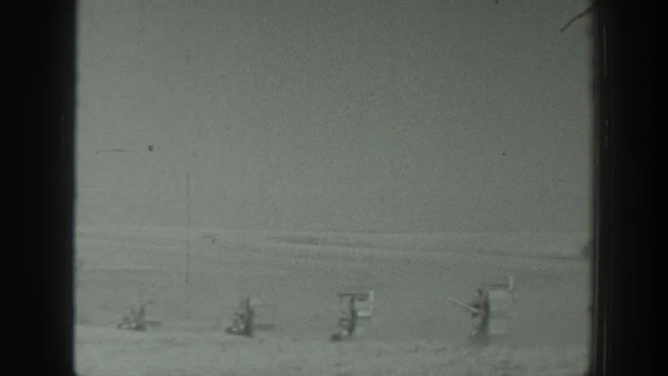 Faded 1939 California home-movie frame showing a pale snowy field with indistinct distant upright forms and visible film wear.