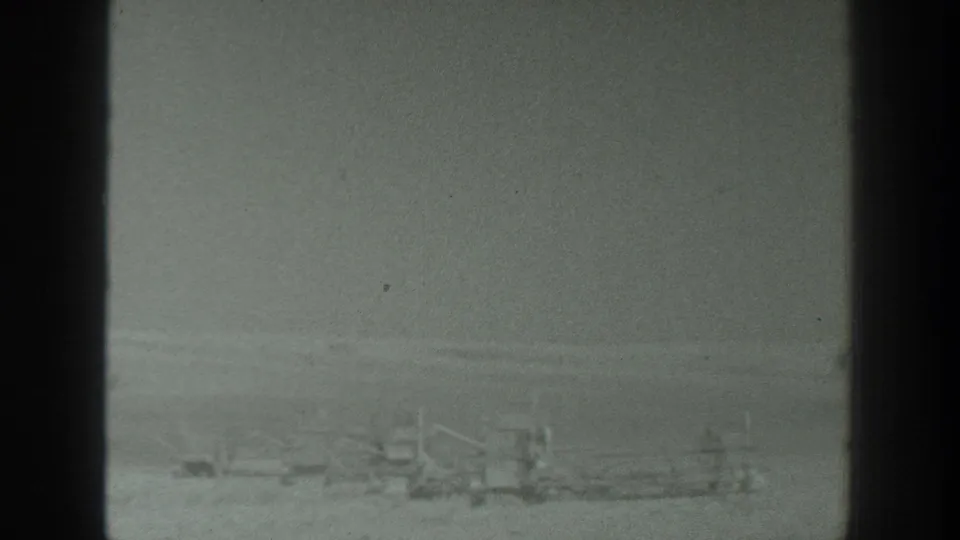 Soft, grainy 8mm frame from 1939 California showing low rail-like structures and indistinct apparatus in open terrain.