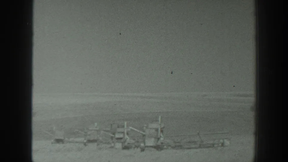 1939 California 8mm view of low equipment-like forms and rail-like shapes on open ground, with soft exposure and visible film wear.