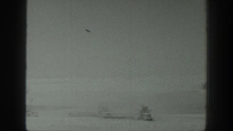 1939 8mm home-movie frame of a broad California field, with a small piece of machinery or equipment barely visible in the distance.