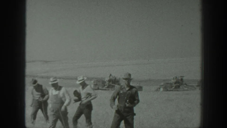 Men in farm clothing walk through a California field in 1939, with early agricultural machinery visible across the background.