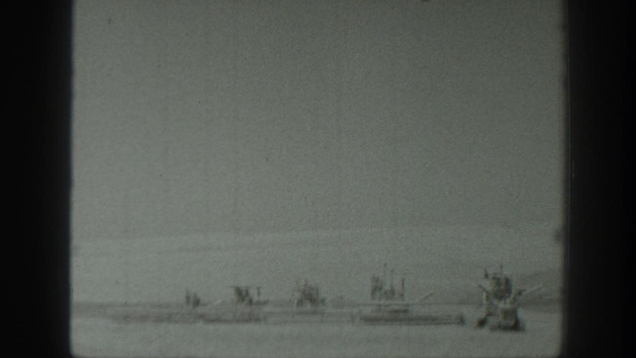 Small boats floating on calm water beneath a pale overcast sky.