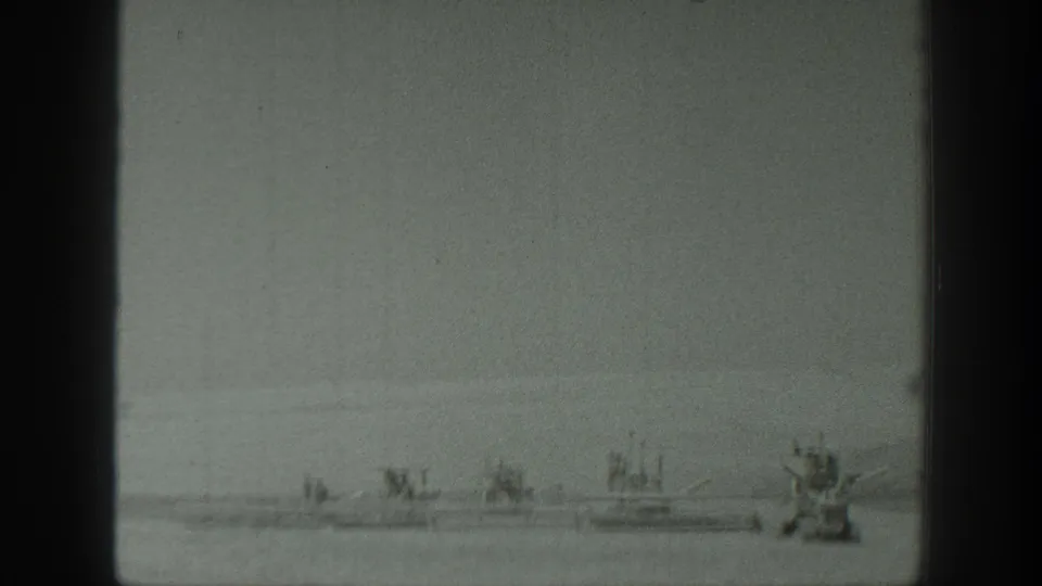 1939 California 8mm frame showing distant small boats and a larger craft on calm water under a hazy sky.