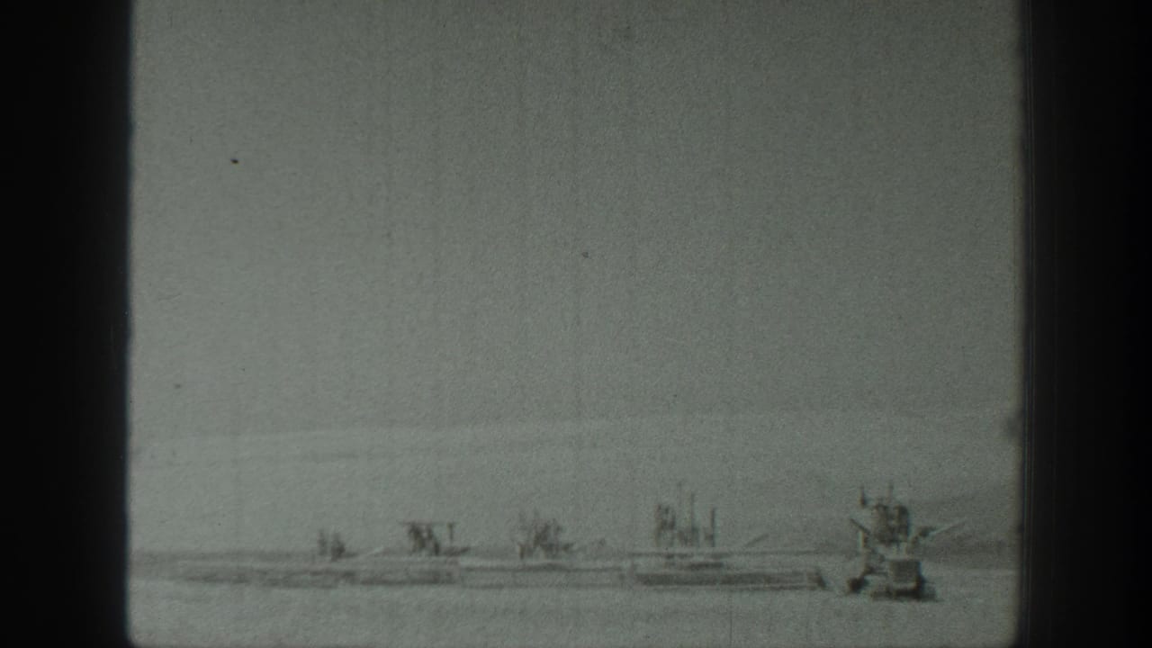 Line of distant boats with a larger craft at the right edge of the water.