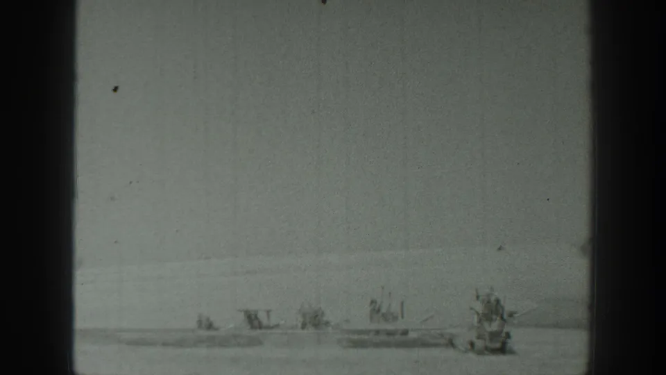 1939 California 8mm frame showing a quiet waterfront view with multiple small boats and a larger craft to the right.