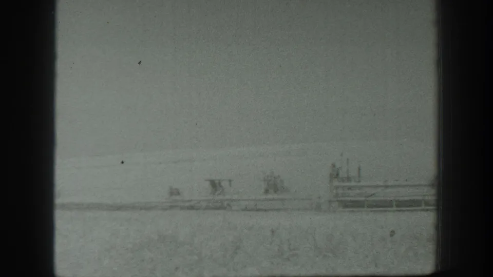 Wide 1939 California home-movie view of a distant vehicle or equipment in a rural field, framed by dark film edges.