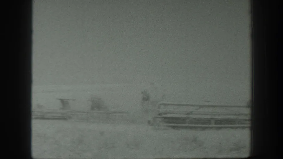 Soft 1939 California home-movie frame showing distant equipment across a rural field with visible film-edge intrusion.