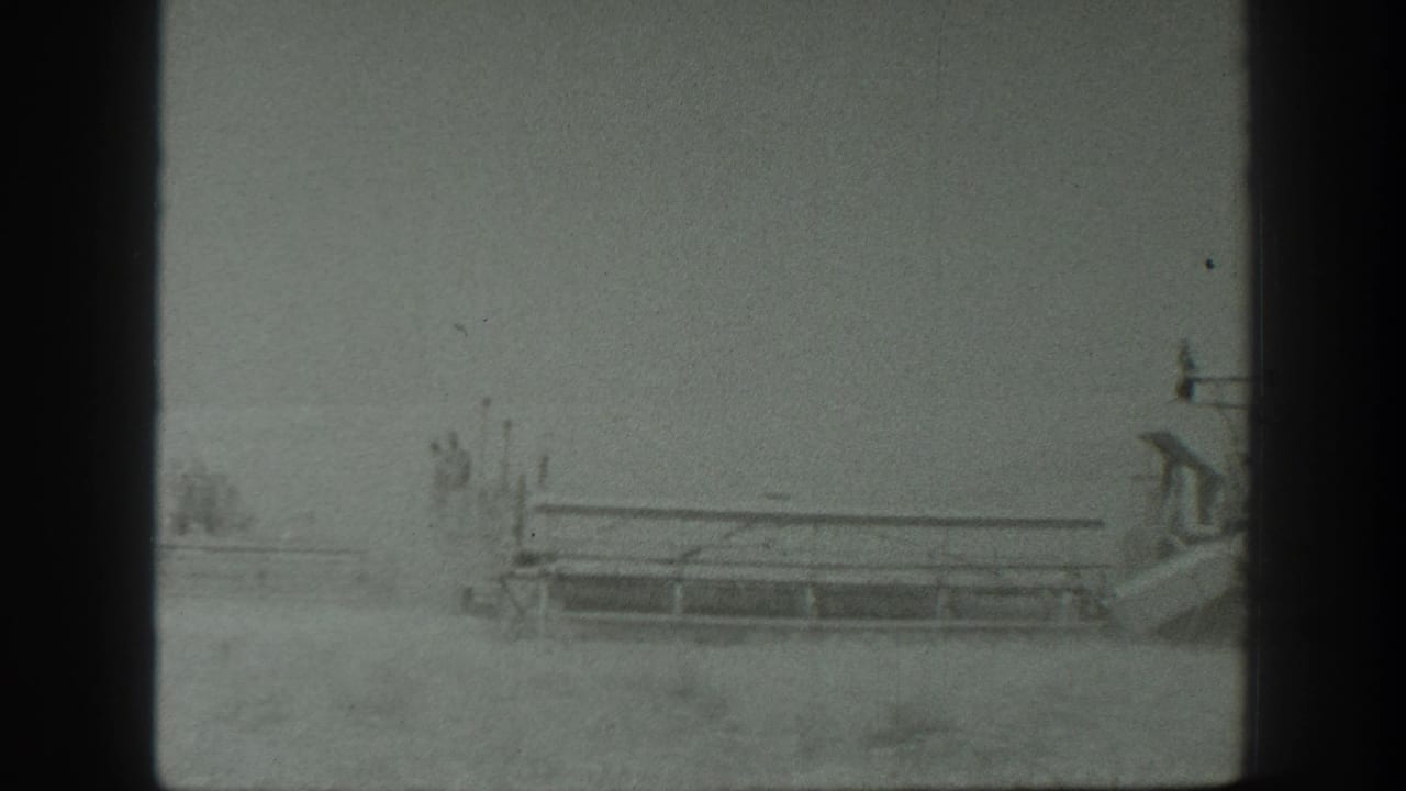 Tractor and combine harvester moving through a dusty grain field.