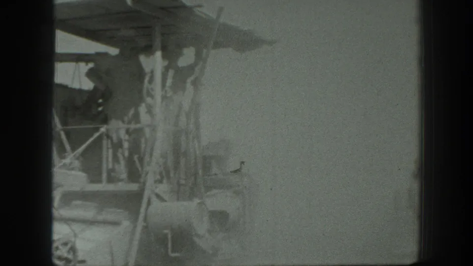 1939 California footage frame showing a wooden-framed vehicle or raised platform with indistinct figures below and bright haze around the structure.