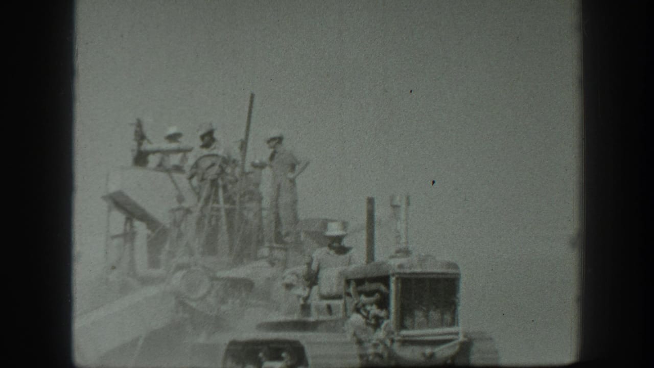 In 1939 California home-movie footage, a tractor driver appears near several men standing on a large field cutter.