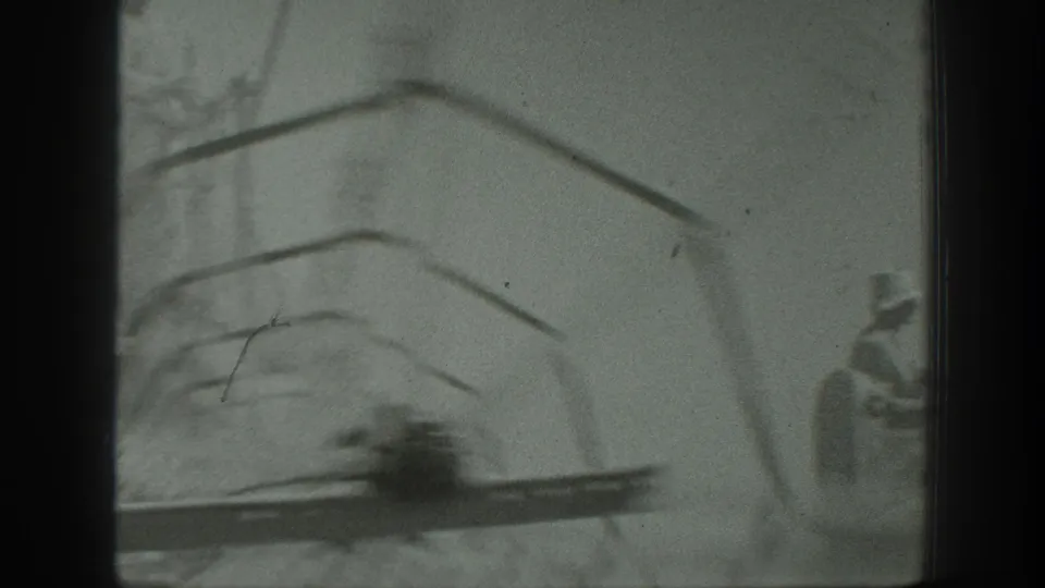 1939 California home-movie frame showing part of a threshing machine in a wheat field, with a worker partly visible near the right edge.