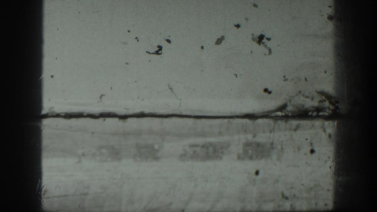 Black-and-white 8mm frame with visible film wear and a partly obscured outdoor scene from the 1939 California home movie.
