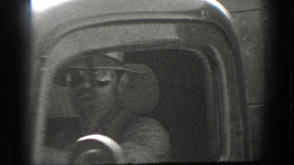 A hat-wearing driver is seen through the side window of a 1930s vehicle in 1939 California footage.