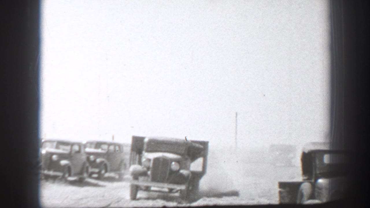 Military-style trucks parked in a dusty field behind dark vertical framing.