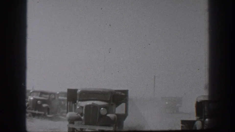 1939 California 8mm view of military-style trucks lined up in dust, partially blocked by a dark vertical foreground shape.