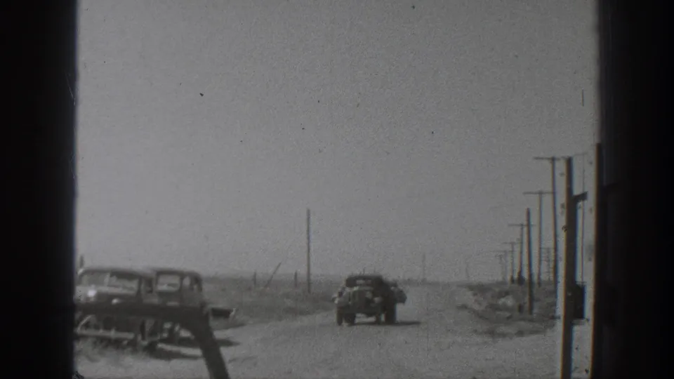 A 1939 California roadside view shows parked cars, utility poles, open ground, and the edge of a work area.