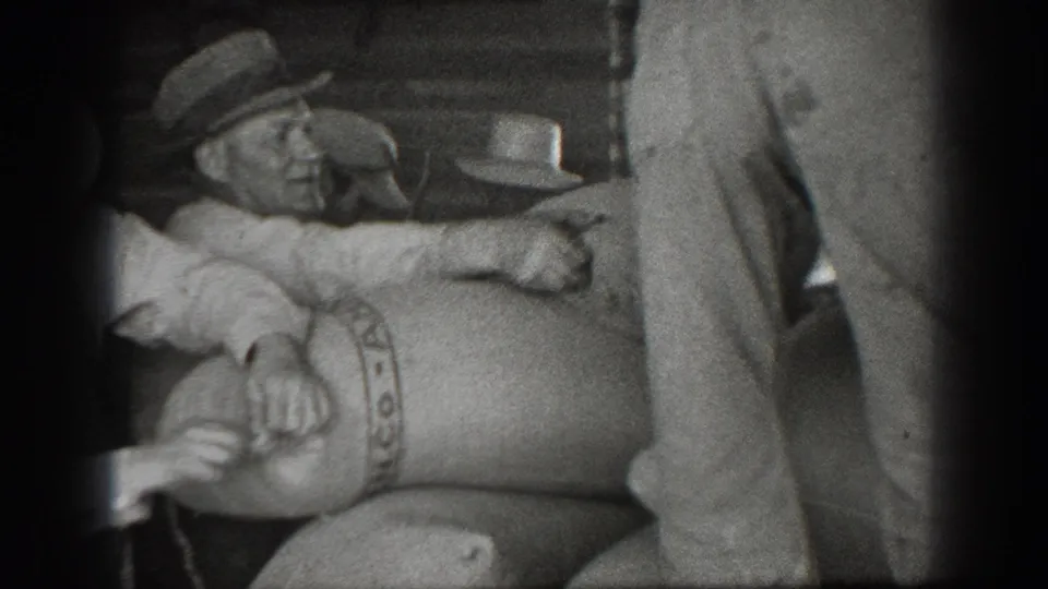 Men in brimmed hats handle a large PANCO-marked sack in a 1939 California warehouse or storage setting.