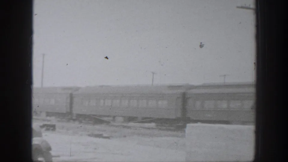 1939 California home-movie frame with passenger cars moving along tracks, softened by blur, grain, and dark edge borders.