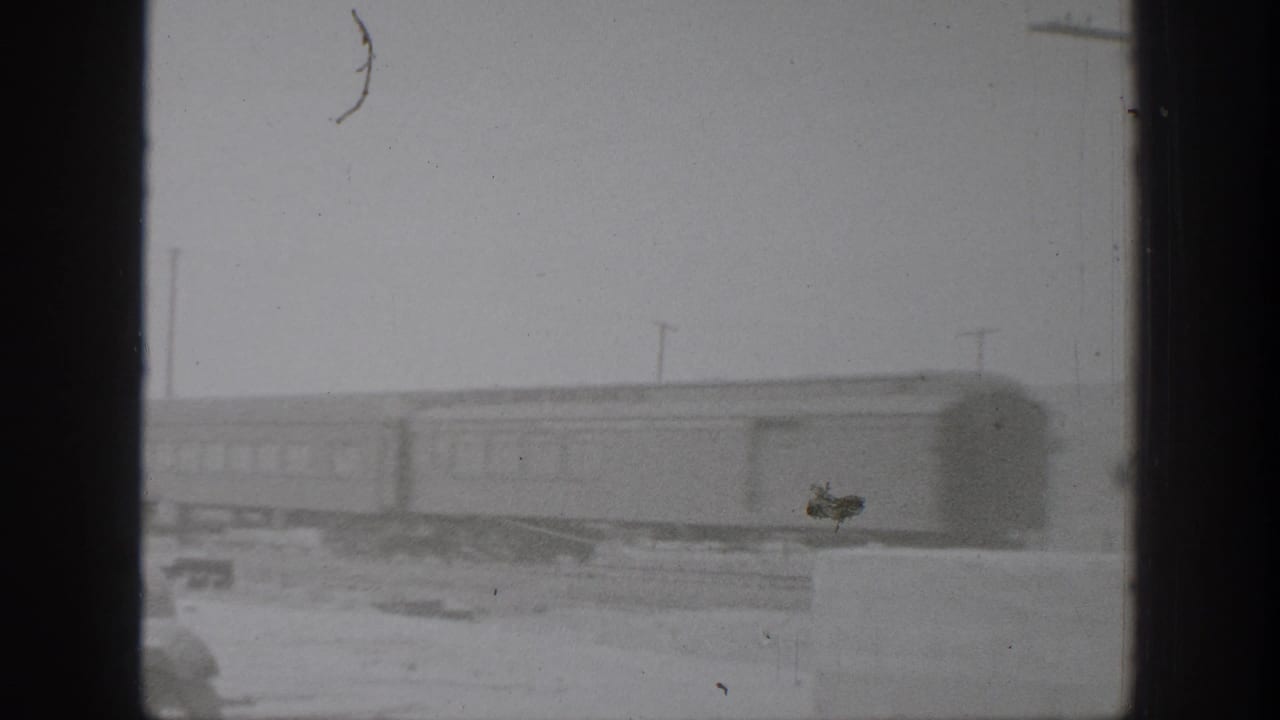 Black-and-white 1939 California 8mm frame showing a train on a dusty rural track through heavy window-like framing.