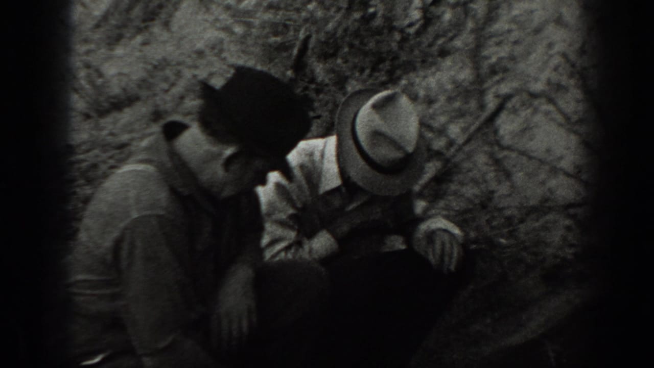 Two adult men in hats crouch near dense brush in 1939 California home-movie footage.