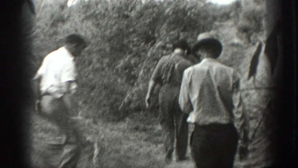 1939 California 8mm footage shows three men in light shirts and hats walking away on a brush-lined dirt path.