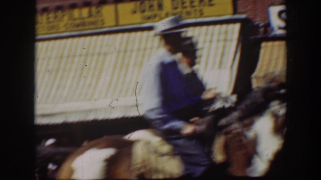 1939 California street view with a hat-wearing rider moving past striped storefront awnings and commercial signs.