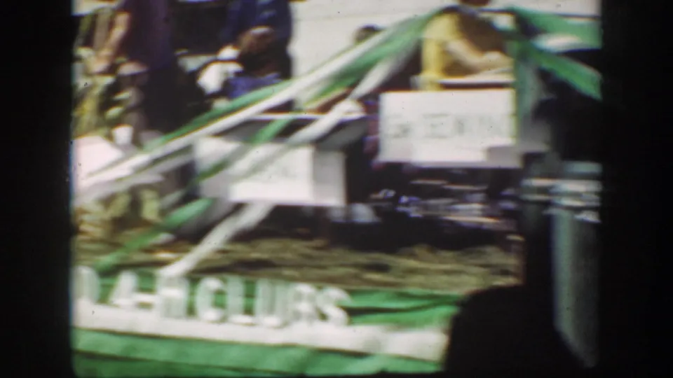 Horse-drawn wagon decorated with streamers and signs moves through the 1939 California street scene.