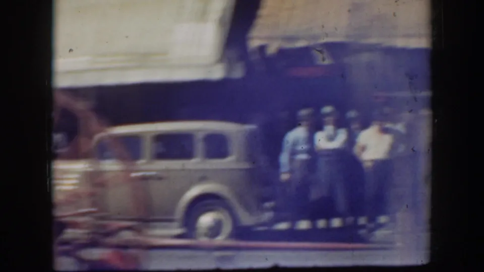 Soft, blue-tinted frame showing a rounded car and several pedestrians near a storefront in California, 1939.