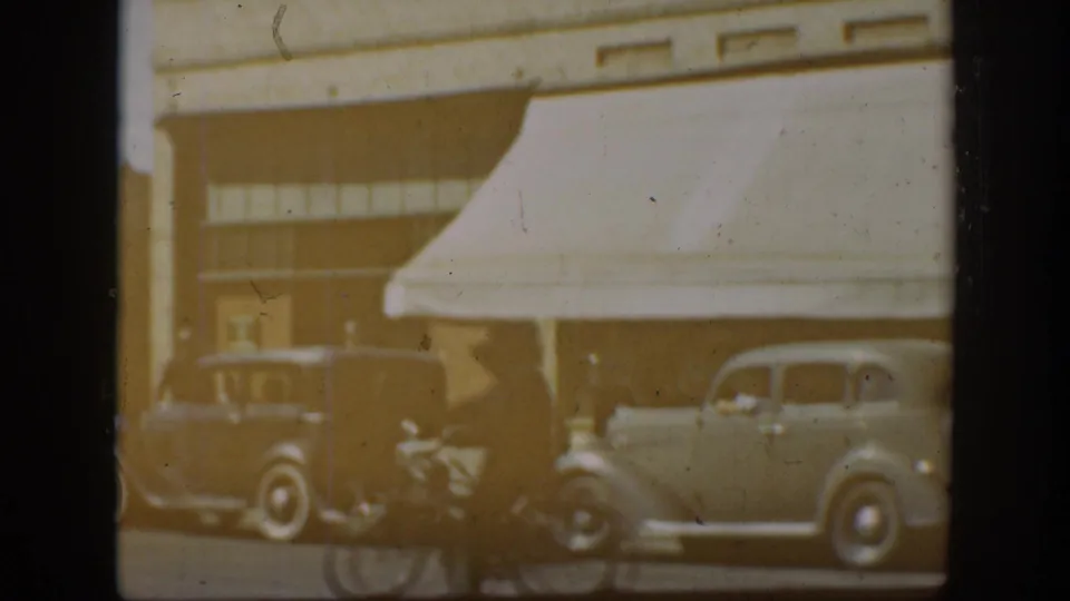 1939 California Main Street view with prewar automobiles, storefront awnings, and soft 8mm exposure.