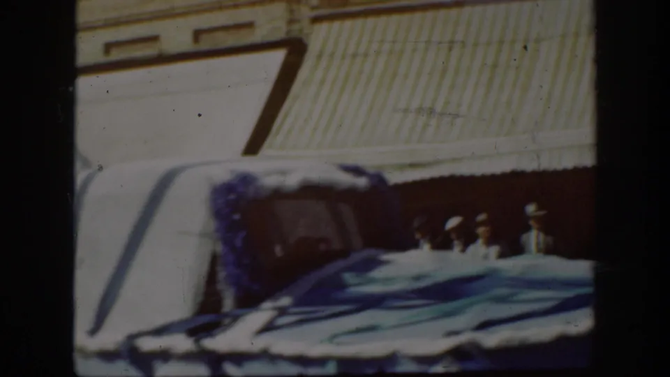 1939 California parade frame showing a decorated vehicle or float with blue draping near Main Street storefronts.