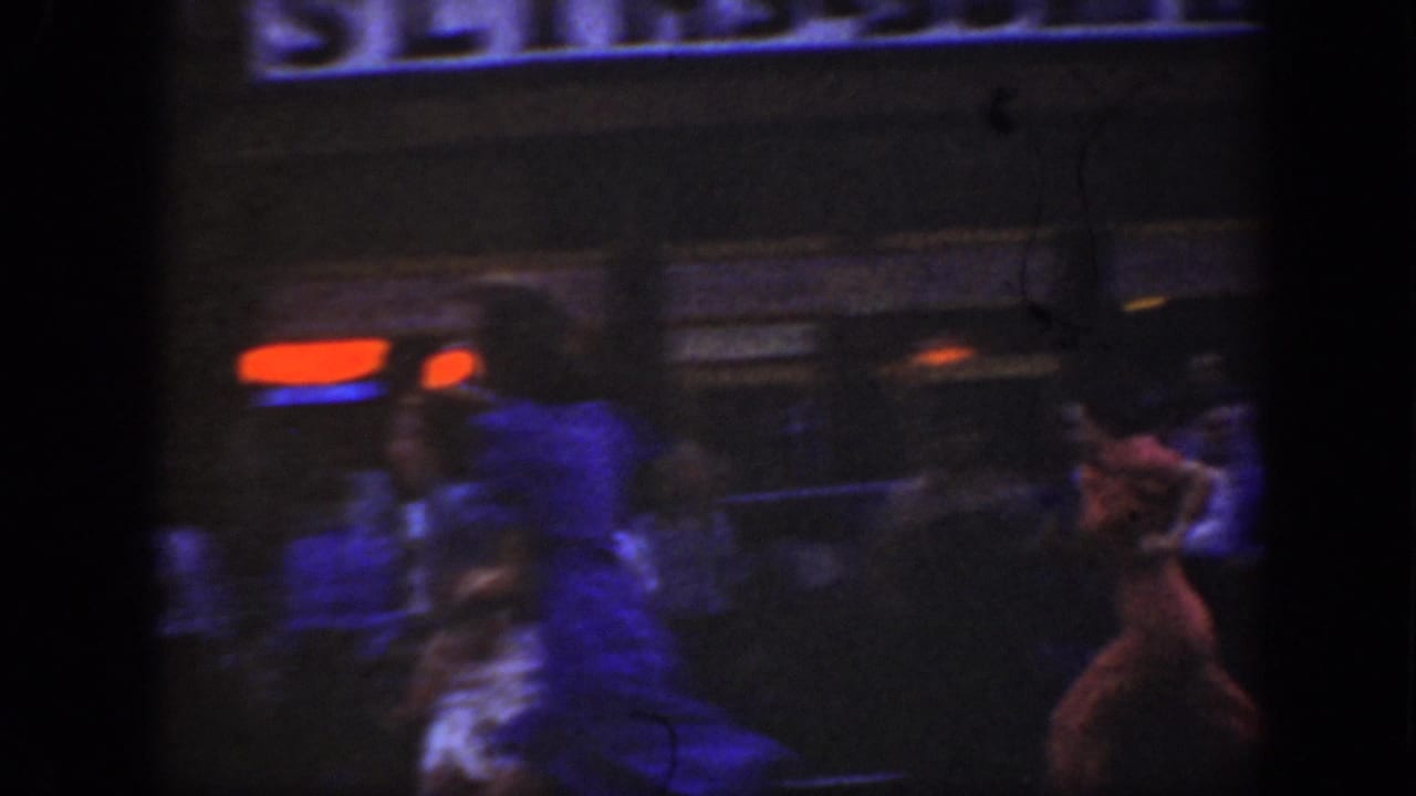 Dim storefront scene with blurred pedestrians and a bright sign near the top of the frame.