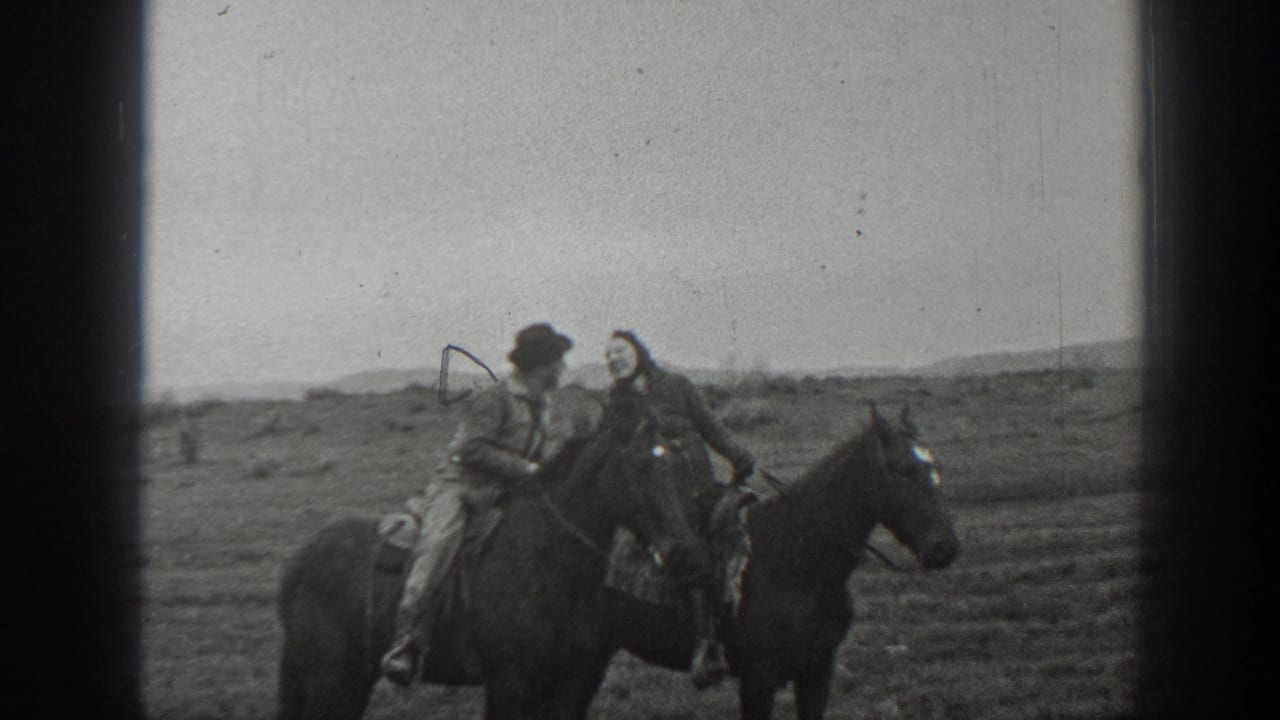 In the supplied 1939 Montana 8mm home-movie footage, a man in a hat and a woman in a long coat sit on separate horses and lean together on open plains.