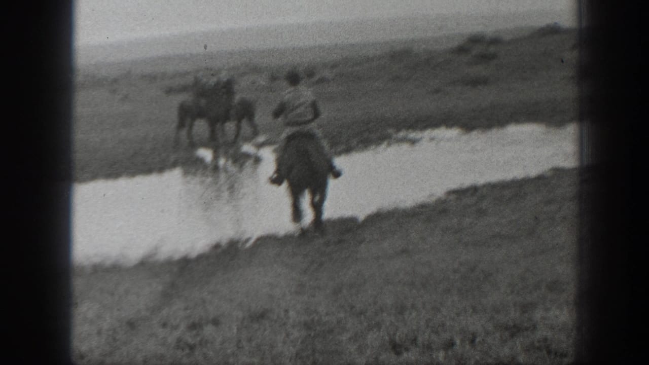 Black-and-white 1939 Montana frame of a rider on horseback moving behind horses across a shallow waterway.