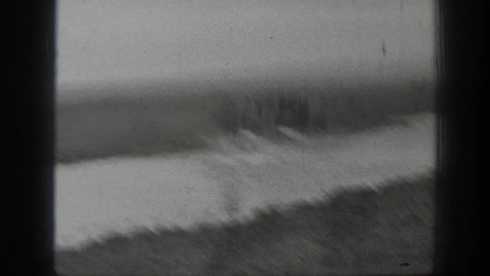 Soft, blurred 1939 Montana 8mm frame with a rider and horses near shallow water and a grassy bank.