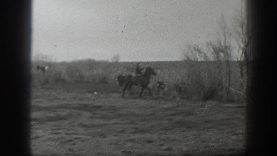 A distant rider on horseback moves past cattle near brush, continuing the supplied 1939 Montana ranching scene.